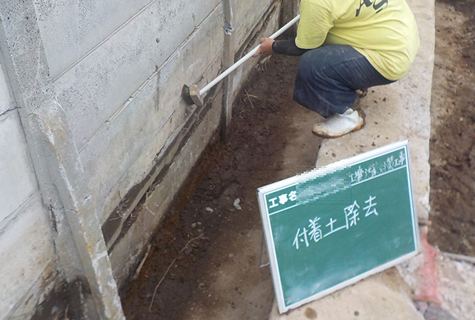 掘削範囲の境界の壁に付着した汚染土壌の清浄作業。